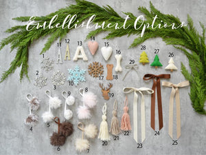 a variety of Christmas-themed embellishment options, including pom-poms, ribbons, and other ornaments arranged on a gray background.