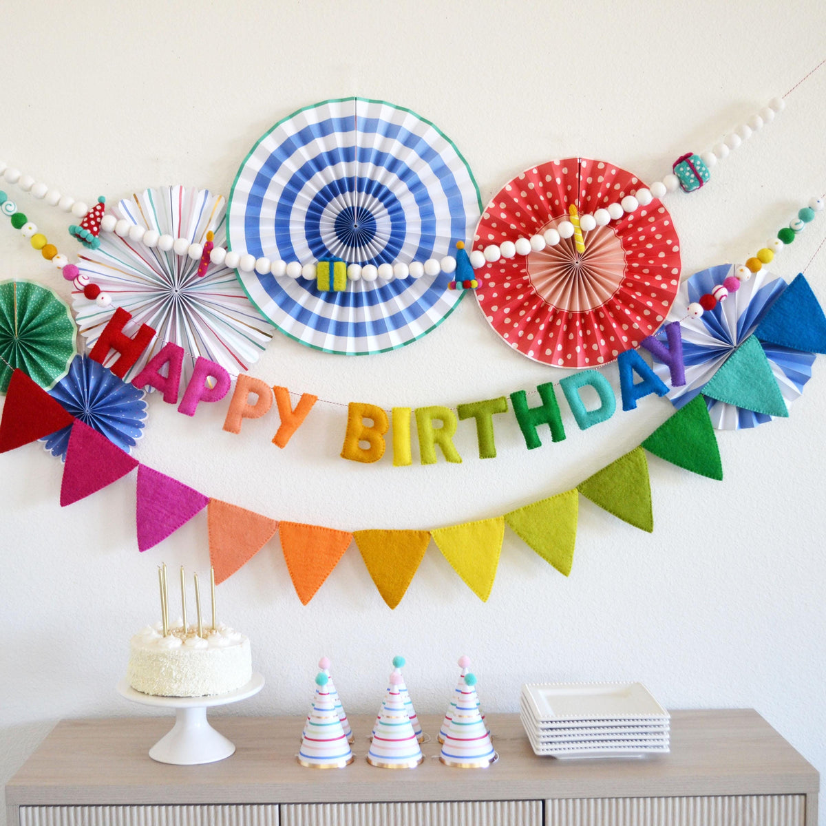 A birthday party setup with a cake, party hats, and a banner that says "Happy Birthday".