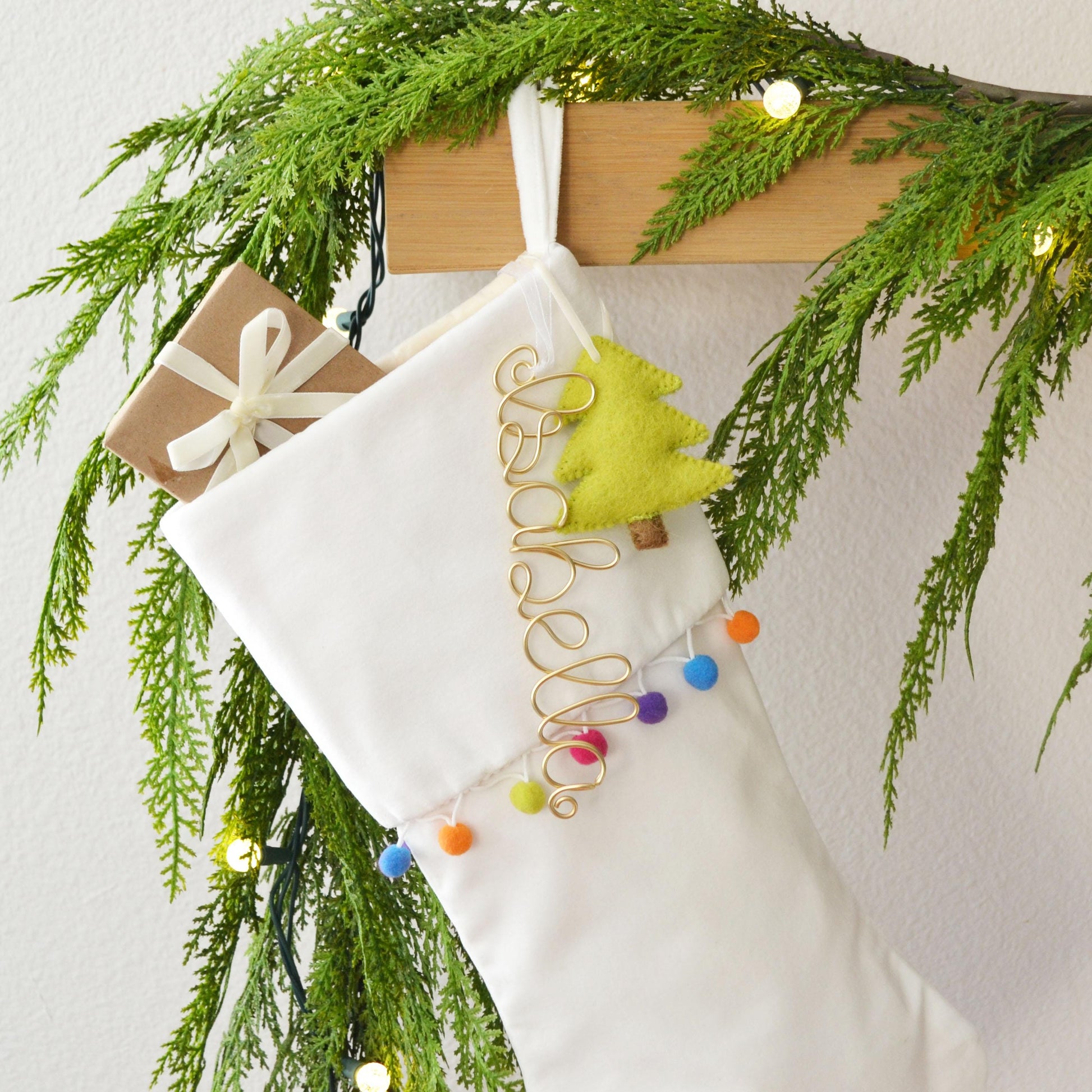 A white Christmas stocking decorated with a green wreath, colorful ornaments, and a yellow star ornament.