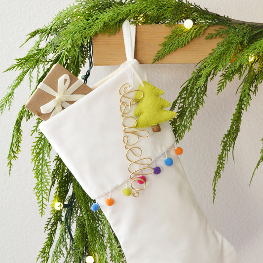 A white Christmas stocking decorated with a green wreath, colorful ornaments, and a yellow star ornament.